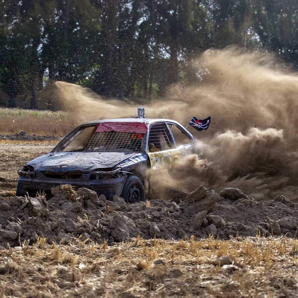 Autocross auto met startnummer 032 drift door een enorme stofwolk op de kleibaan tijdens Autocross Zeeland in Hoek